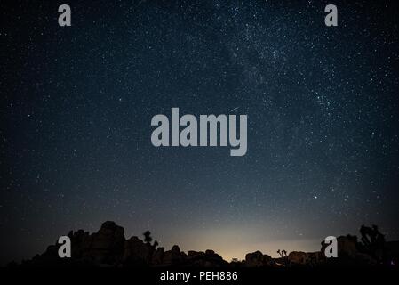 Joshua Tree, California, USA. 13th Aug, 2018. 2018 Perseid meteor shower at Joshua Tree National Park with Milky Way visible and glow on the horizon. Credit: Stan Sholik/ZUMA Wire/Alamy Live News Stock Photo