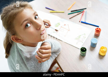 Lonely girl is drawing. Photo of cute schoolgirl doing homework. Education concept Stock Photo