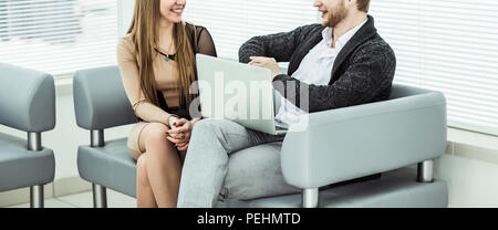members of the business team with a laptop, discussing work problems sitting on the office sofa Stock Photo