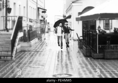 concept of love: loving couple under an umbrella walking down the street of the city.black-and-white photo in retro style Stock Photo