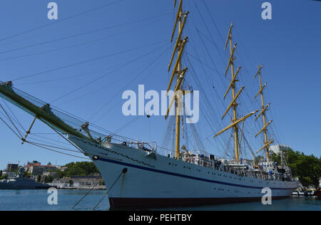 Old yacht with lowered sails moored in the port Stock Photo