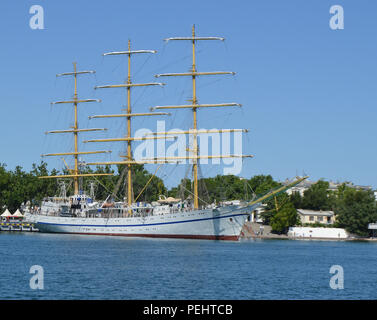 Old yacht with lowered sails moored in the port Stock Photo