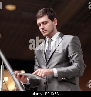 Handsome businessman standing on steps using tablet in office building Stock Photo