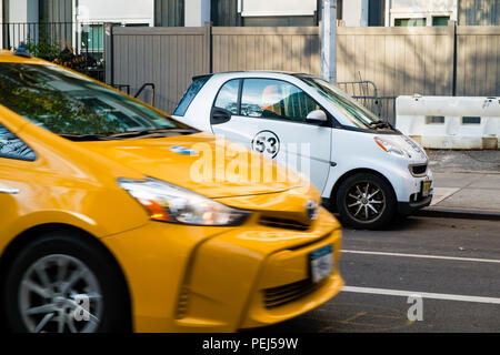 New York yellow taxi passing a Smart Car with Herbie number 53 decal Stock Photo