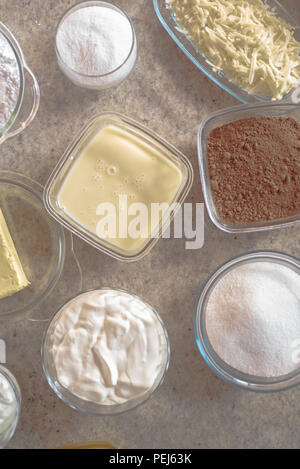 Pots with ingredients for cake, condensed milk, butter, cocoa, chocolate, sour cream, cheese, sugar Stock Photo