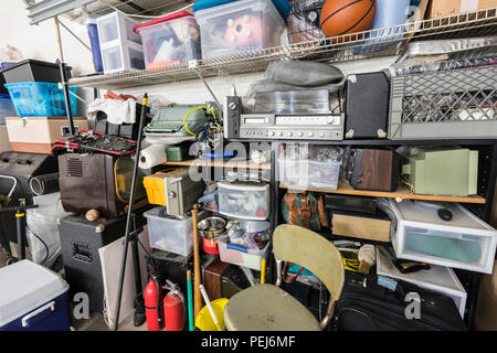 Full shelves of vintage electronics, boxes and sports equipment in typical suburban garage. Stock Photo