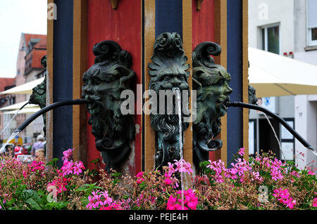 bronze gargoyles spitting water at fountain with flower boxes at market place in Ulm, Germany Stock Photo