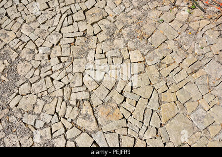 Abstract pattern of new granite cobblestone paving setts being filled with stone dust between the setts Stock Photo