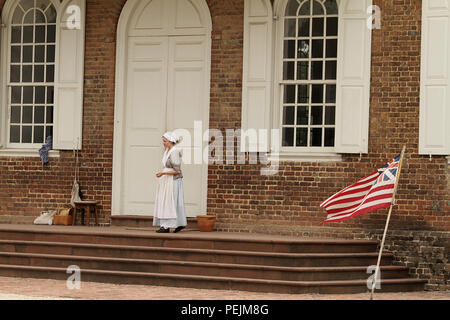 Woman reenactor in Colonial Williamsburg, Virginia. The Grand Union flag, the first national flag of the United States of America. Stock Photo