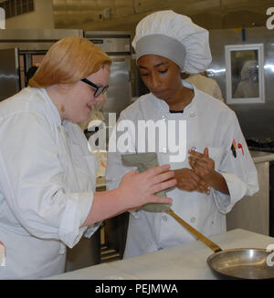 Student chefs Emily Petersen (left) and Mya Toney (right) how to use an MRE food component to prepare a meal at a Boards of Cooperative Educational Services (BOCES) vocational education facility in Goshen, N.Y., Dec. 4, 2015. The students prepared meals with MREs as part of a New York Army National Guard educational challenge designed to test their skills and familiarize them with Army careers. Petersen is a junior at Middletown High School and Toney is a junior at Port Jervis High School. (U.S. Army National Guard photo by Master Sgt. Raymond Drumsta/released) Stock Photo