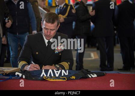 151208-N-NU281-024 MEDITERRANEAN SEA (Dec. 8, 2015) Capt. Ryan Scholl, commanding officer of aircraft carrier USS Harry S. Truman (CVN 75), autographs a Navy soccer jersey for a guest touring Truman during a reception held in Truman's hangar bay. Harry S. Truman Carrier Strike Group is conducting naval operations in the U.S. 6th Fleet area of operations in support of U.S. national security interests in Europe and Africa. (U.S. Navy photo by Mass Communication Specialist 3rd Class J. R. Pacheco/Released) Stock Photo