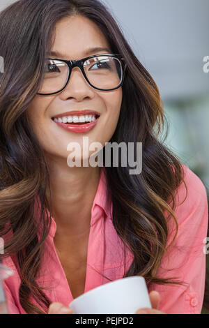 Beautiful young Asian Chinese woman or girl wearing glasses smiling and drinking a cup or mug of coffee Stock Photo