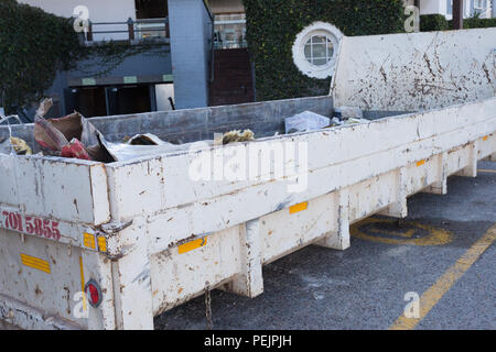 half full skip outside next to a building for removal of rubble and rubbish Stock Photo