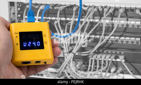 Testing of PoE on cables connected in patch panels of rack case. Human hand detail when gauging structured cabling by a yellow measuring instrument. Stock Photo