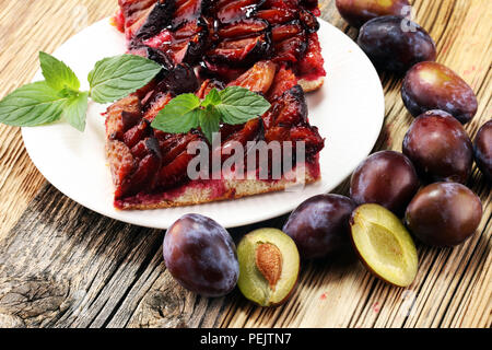 Rustic plum cake on wooden background with plums around Stock Photo