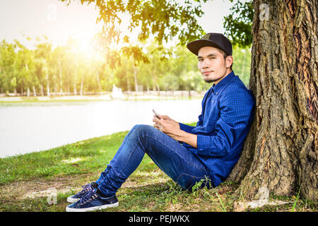 Man blue shirt are using smartphone by internet online,Technology social media everywhere and nature background sunlight Stock Photo