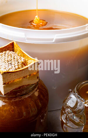 fresh honey in white bucket and in glass jar, with honeycomb Stock Photo