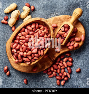 Peeled peanuts in bowl and scoop on gray background. Top view of nuts. Stock Photo
