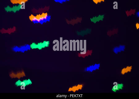 defocused bokeh multicolor lights in shape of bats for halloween background - holidays, decoration and party concept Stock Photo