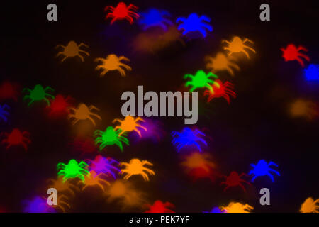 defocused bokeh multicolor lights in shape of spiders for halloween background - holidays, decoration and party concept Stock Photo