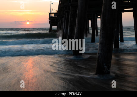 The waves splash along the Sandbridge Fishing Pier in Sandbridge Virginia, Virginia Beach during a sunrise.  Pastel colors and a dreamy look Stock Photo