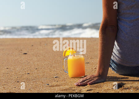 Orange juice with pulp in a jar on the beach near tourist resting, space for text Stock Photo