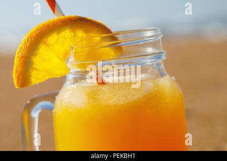 Orange juice with pulp on the beach close-up Stock Photo