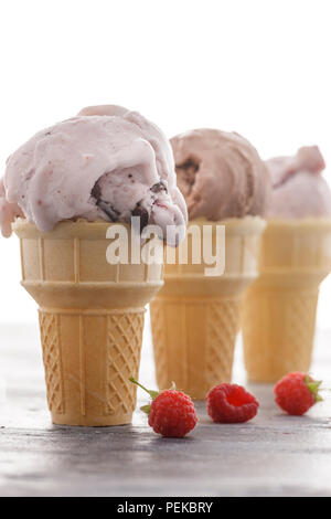 Three ice cream cones and a few raspberries.