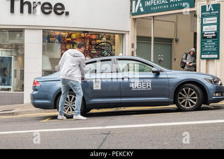 Man takes Uber taxi cab minicab ride on a UK street. Stock Photo