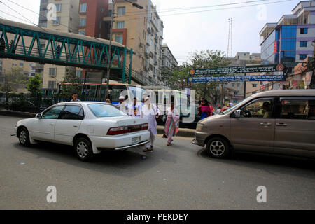 Pedestrians cross a busy road putting their lives at risk. Dhaka, Bangladesh Stock Photo