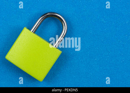 Green padlock isolated on blue background Stock Photo