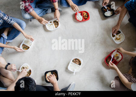 Top view of teamwork and team group concept, Thai Asian people sitting down on floor and enjoying eating fast food that buying from convenience store  Stock Photo