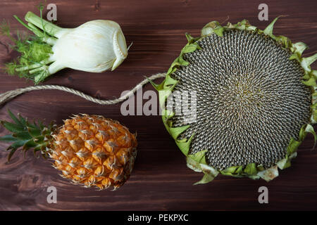 Pineapple, fennel and sunflower head on a brown rustic wood background in a healthy nutritious diet concept Stock Photo
