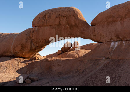 Massive boulder rock arch with smaller rocks gathered on a pile, Spitzkoppe, Namibia Stock Photo