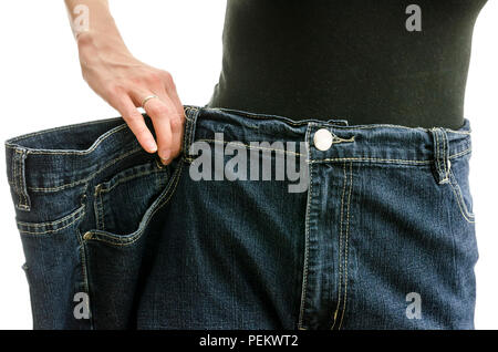 Closeup of a slim woman waist in oversized pants after losing a lot of weight. Over white background. Stock Photo