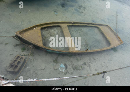 Small sunken boat in harbor submerged in shallow water and moored Stock Photo