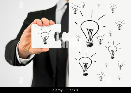 Businessman with the idea for business development holding a puzzle piece with lightbulb on it to perfect his idea. Stock Photo