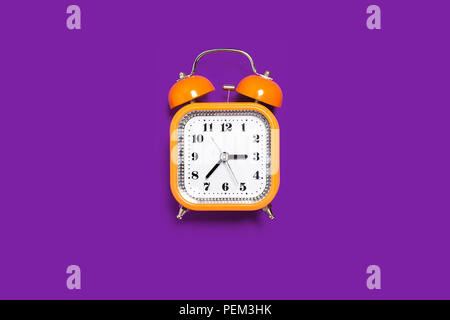 orange alarm clock on the purple background Stock Photo