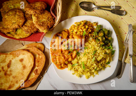 Indian chicken vegetable curry dinner with fried okra biryani rice and corn Stock Photo