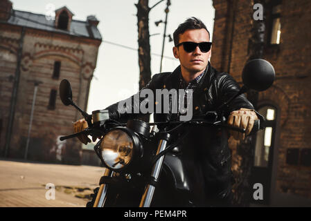 Man sitting on a cafe-racer motorcycle outdoors Stock Photo