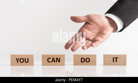 You can do it business concept with copy space. Businessman hand showing wooden blocks with inscription, viewed in close-up against light background. Stock Photo
