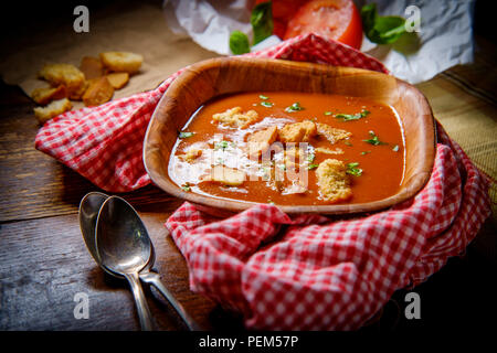 Fresh hot tomato basil soup with croutons in dark moody lighting Stock Photo