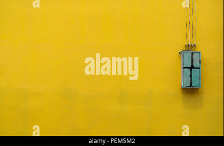 Green wooden box, electric control equipment in the factory on yellow vintage concrete wall background with copy space. Safety in home and factory ind Stock Photo