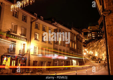 Long exposure night shot of the Neuveville area of Fribourg in Switzerland, with vehicle light trails and public lights Stock Photo