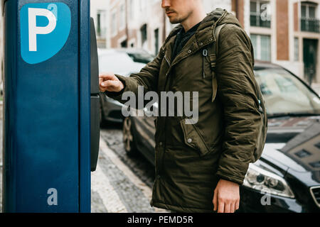 A person or a tourist pays for car parking in a street parking machine. Stock Photo