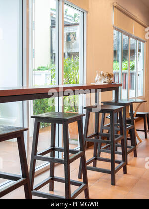 Wooden chairs and wooden counter bar table near the glass window in cafe. Stock Photo