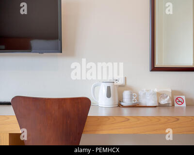Hotel room service set, white prepared coffee cups , clean glass in plastic wrap, tissue paper in the box, no smoking sign and electric kettle on wood Stock Photo
