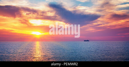 dramatic sunset at the sea with ferry on the background Stock Photo