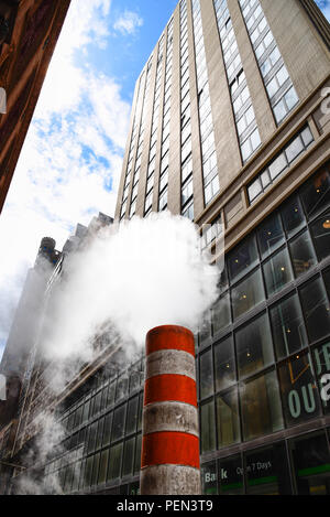 Low angle view of steam coming out stack for venting the district heating system in downtown of New York Stock Photo