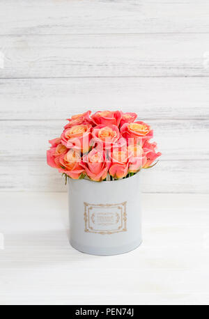Beautiful pink roses in a round box. Peach roses in a round box. Roses in a round box on a white wooden background. Roses in a Hat Box Stock Photo